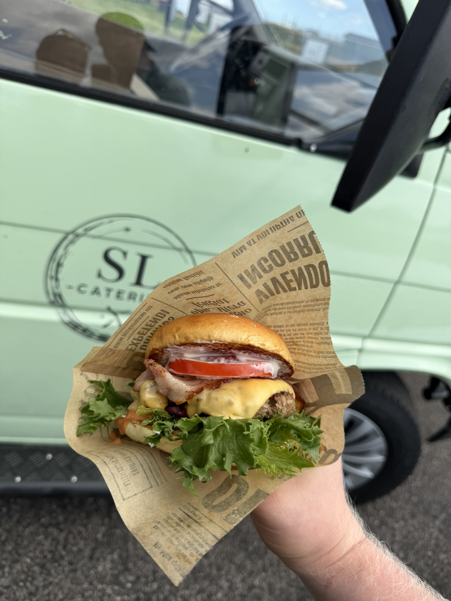Värskelt valmistatud burger SL Cateringi rohelise toiduauto taustal
